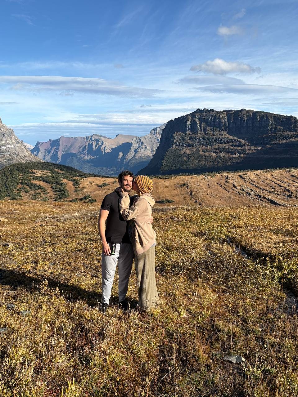 Therese kissing Thomas on the cheek in a golden alpine meadow