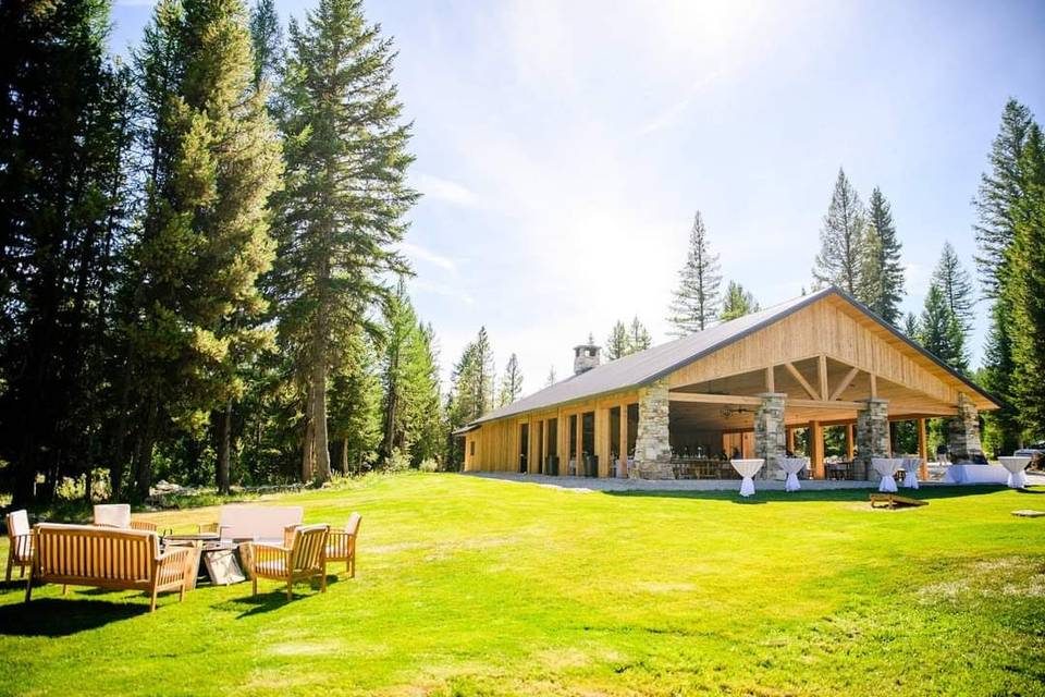 The timber and stone pavilion at Star Meadows Ranch, set on a green lawn among tall pines